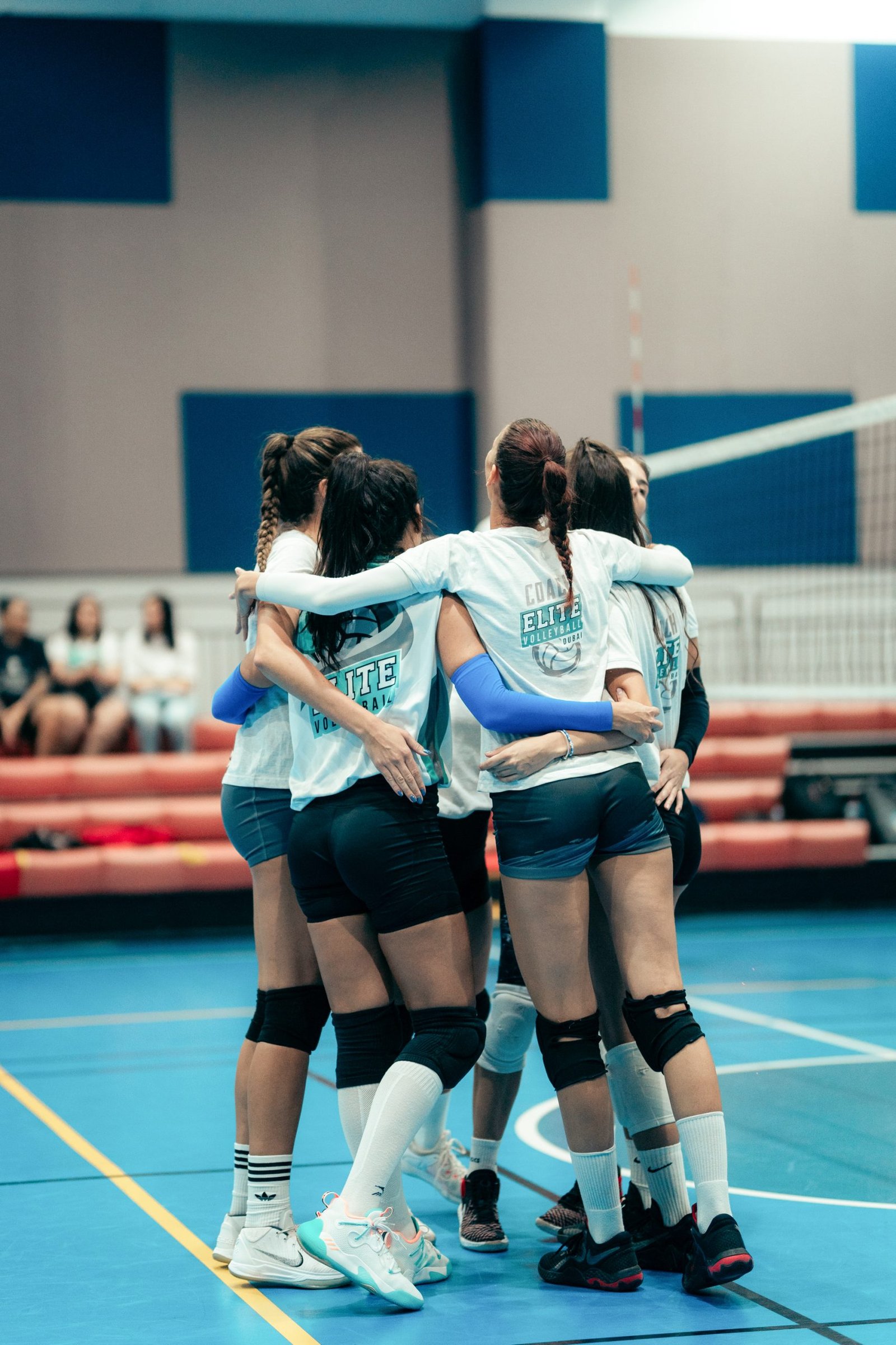 Youth volleyball teammates huddling together on the court