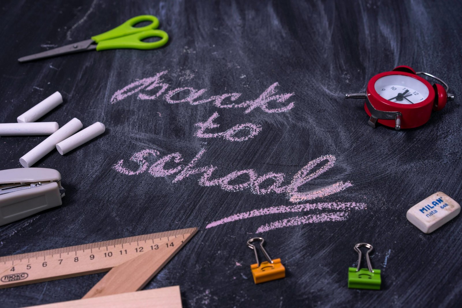School supplies and an alarm clock surrounding a Back to School message on a chalkboard