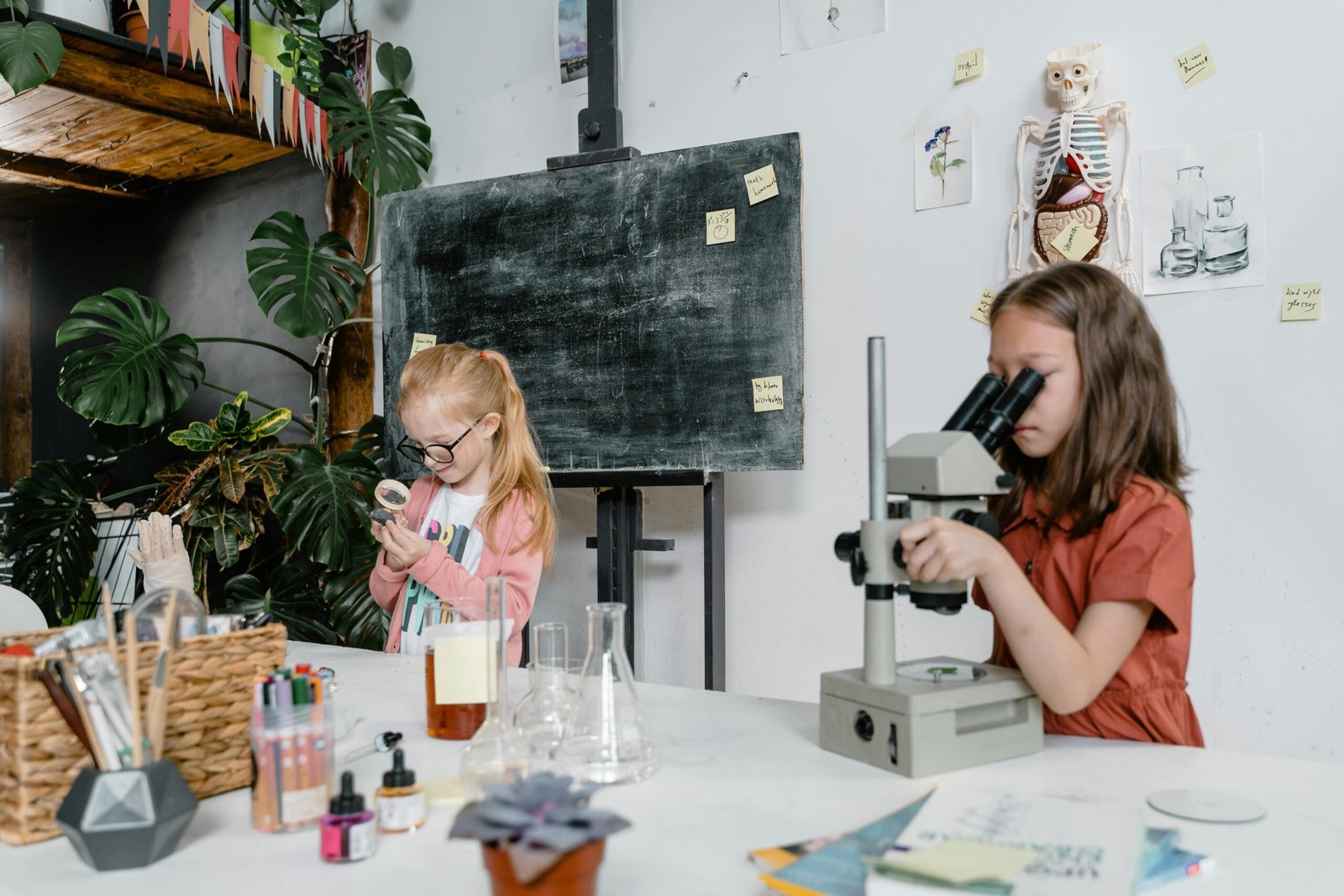 Two children exploring science with a microscope and magnifying glass