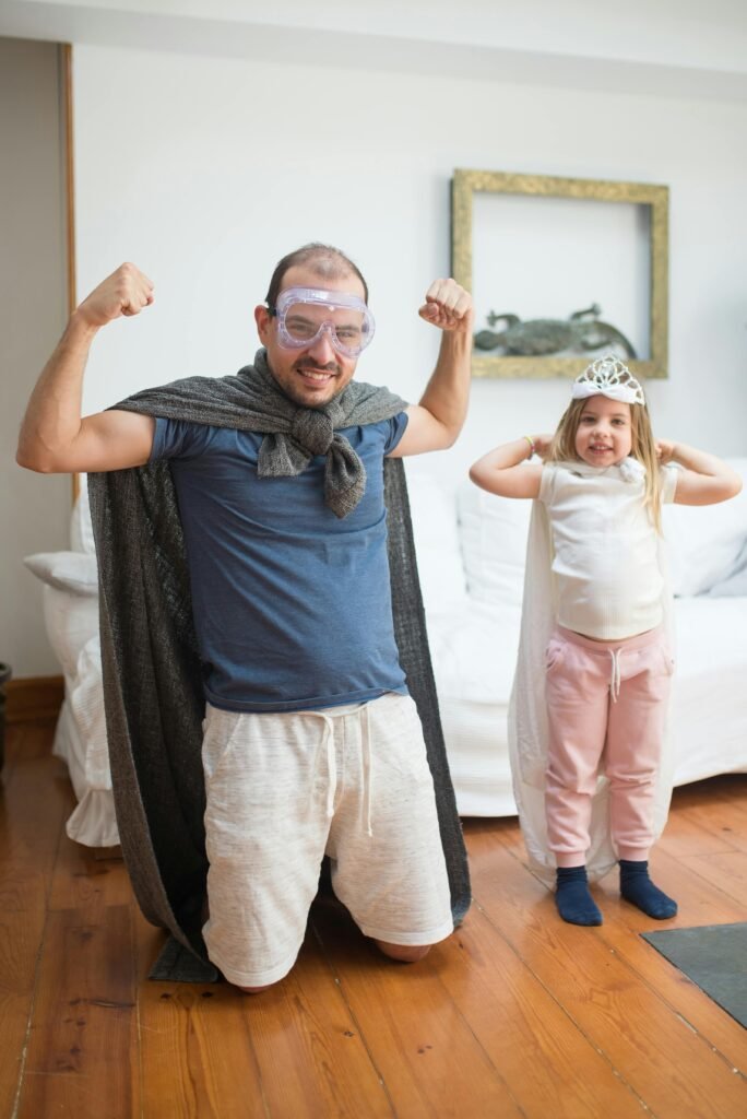 Father and daughter dressed as superheroes posing in a playful setting.