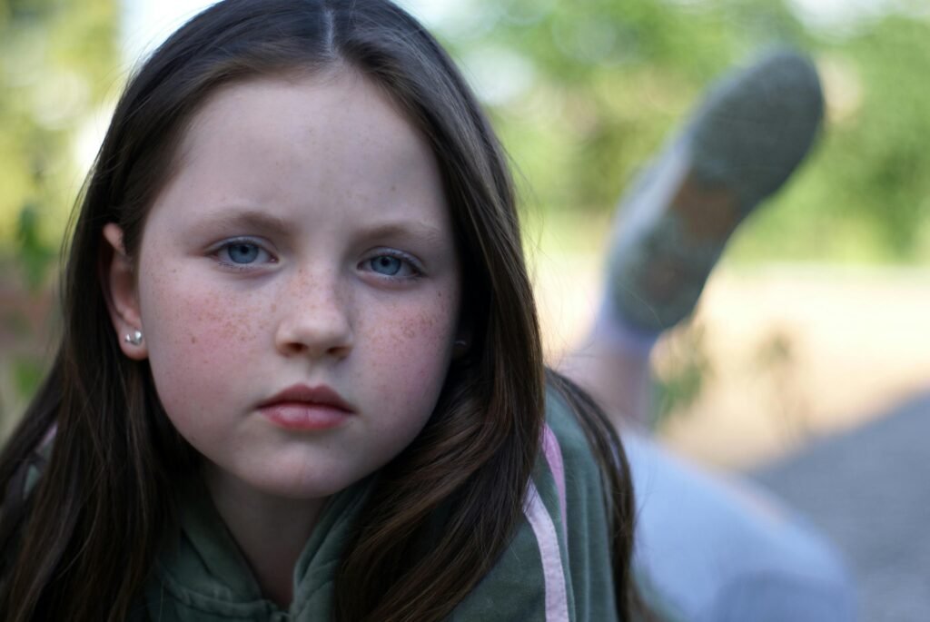 Serious young girl with freckles lying outdoors in a reflective mood.