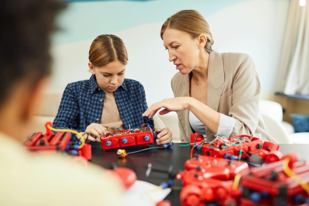 A teacher guides a student through assembling a robotics project, emphasizing teamwork and hands-on learning.