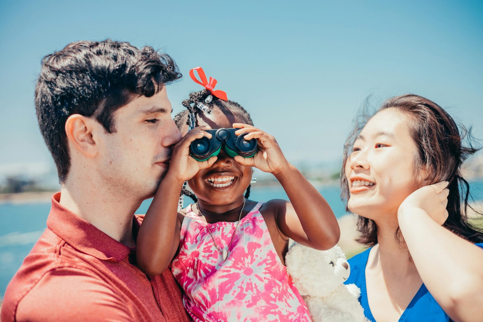 Parents helping a young child look through binoculars outdoors