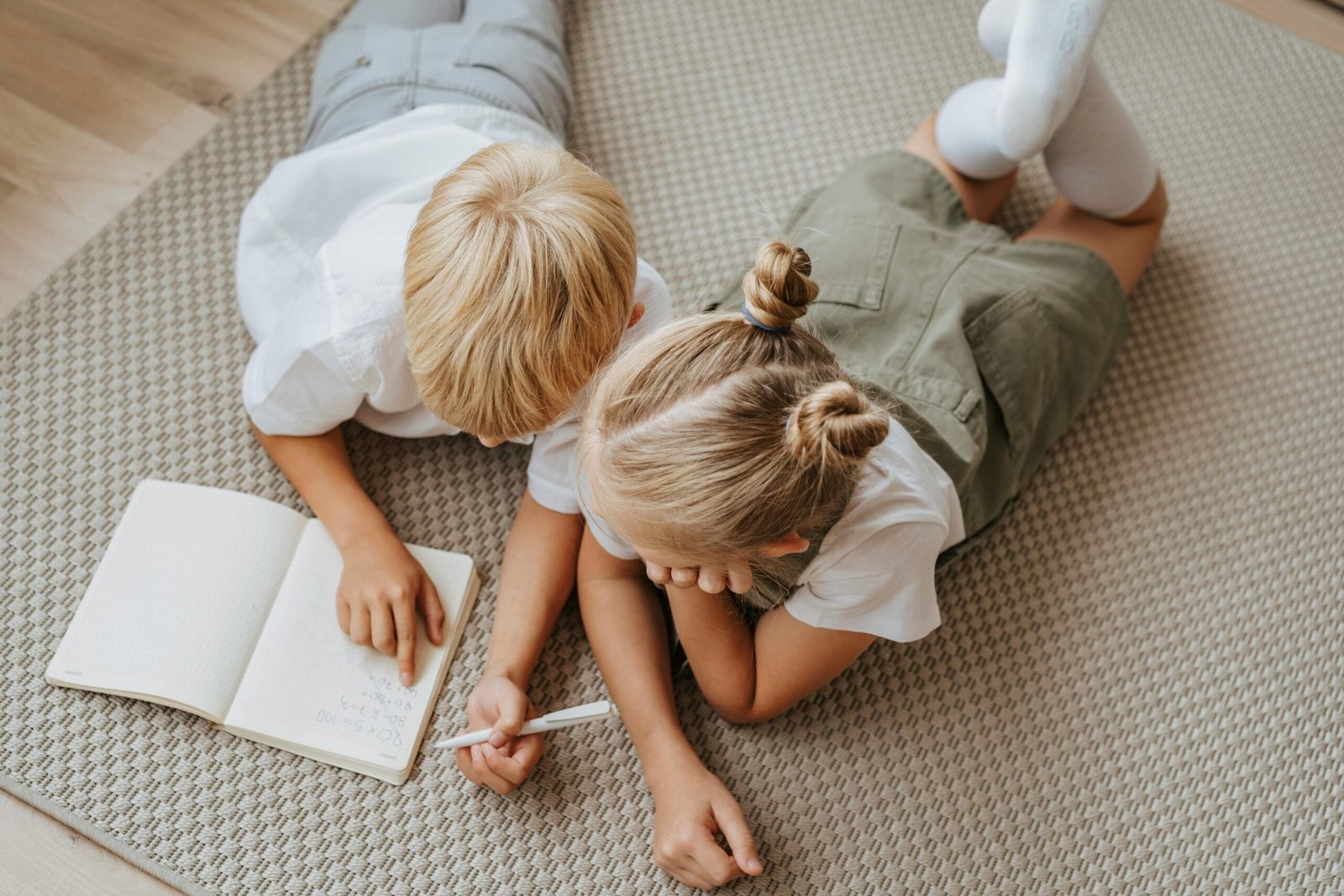 Two children completing homework together on the floor