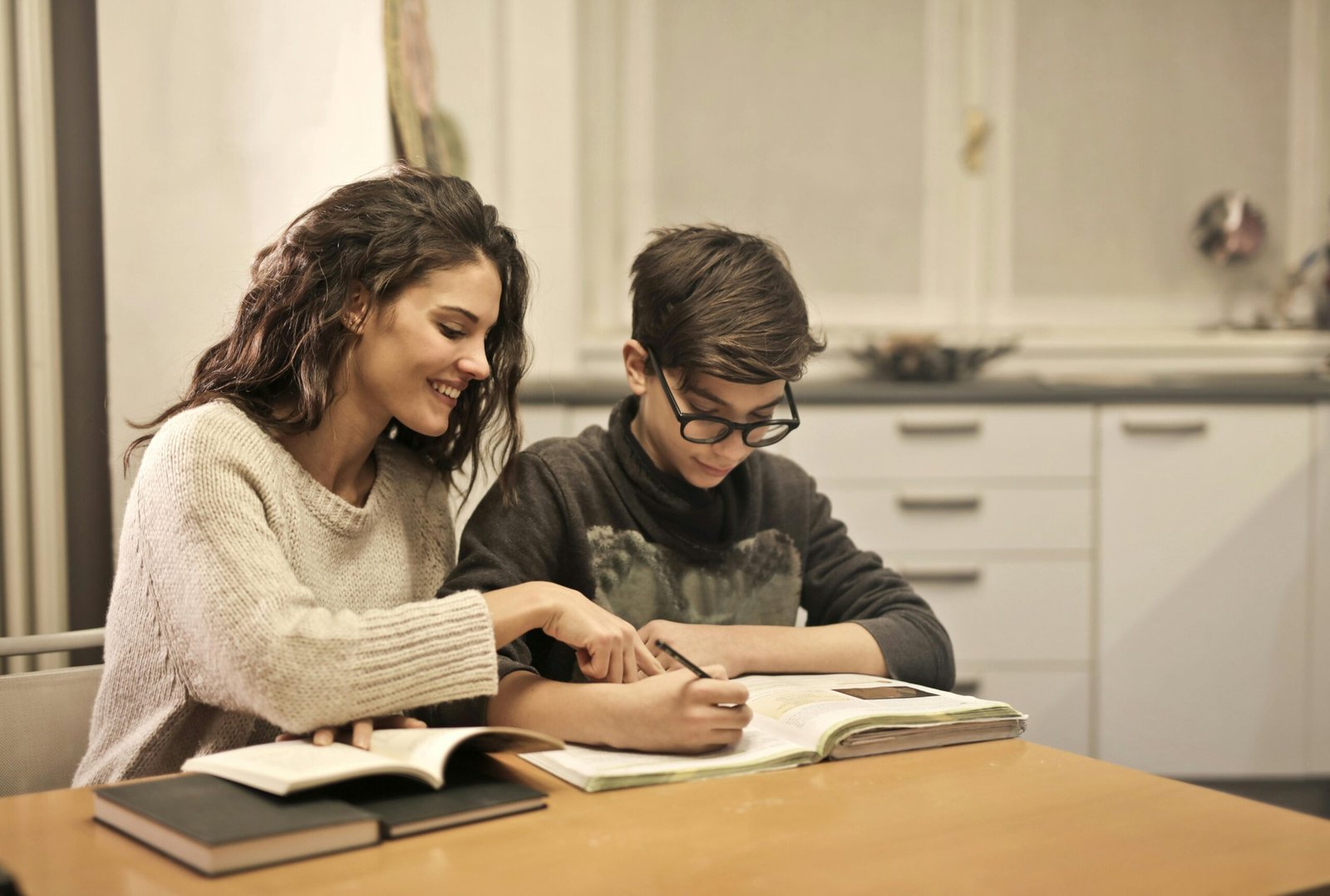 Parent guiding a child through homework at a kitchen table